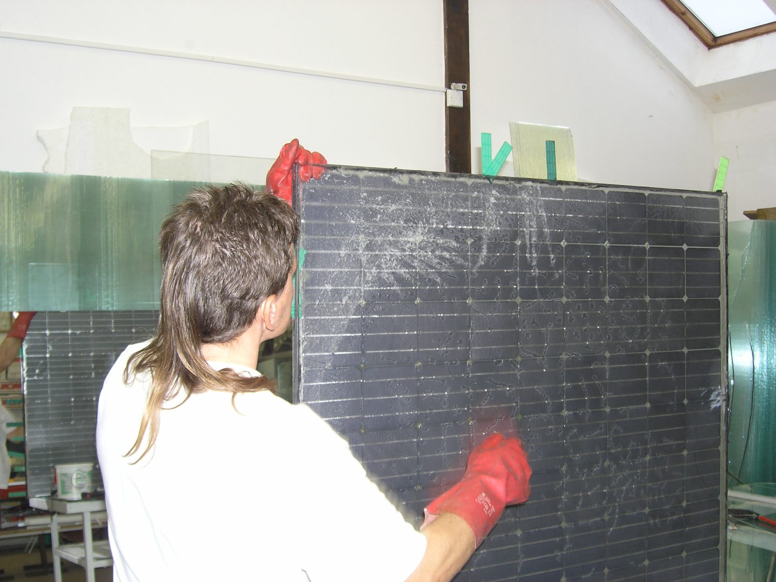 End-of-life recovery — a technician disassembling a silicone-gel PV panel into clean glass sheets, photographed by Vladislav Poulek.