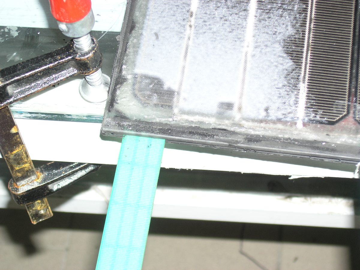 A clamp holding a panel as the gel laminate is separated from the glass at room temperature.