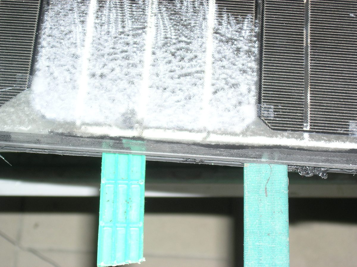 Close-up of softened silicone gel residue lifting cleanly from the recovered glass surface.