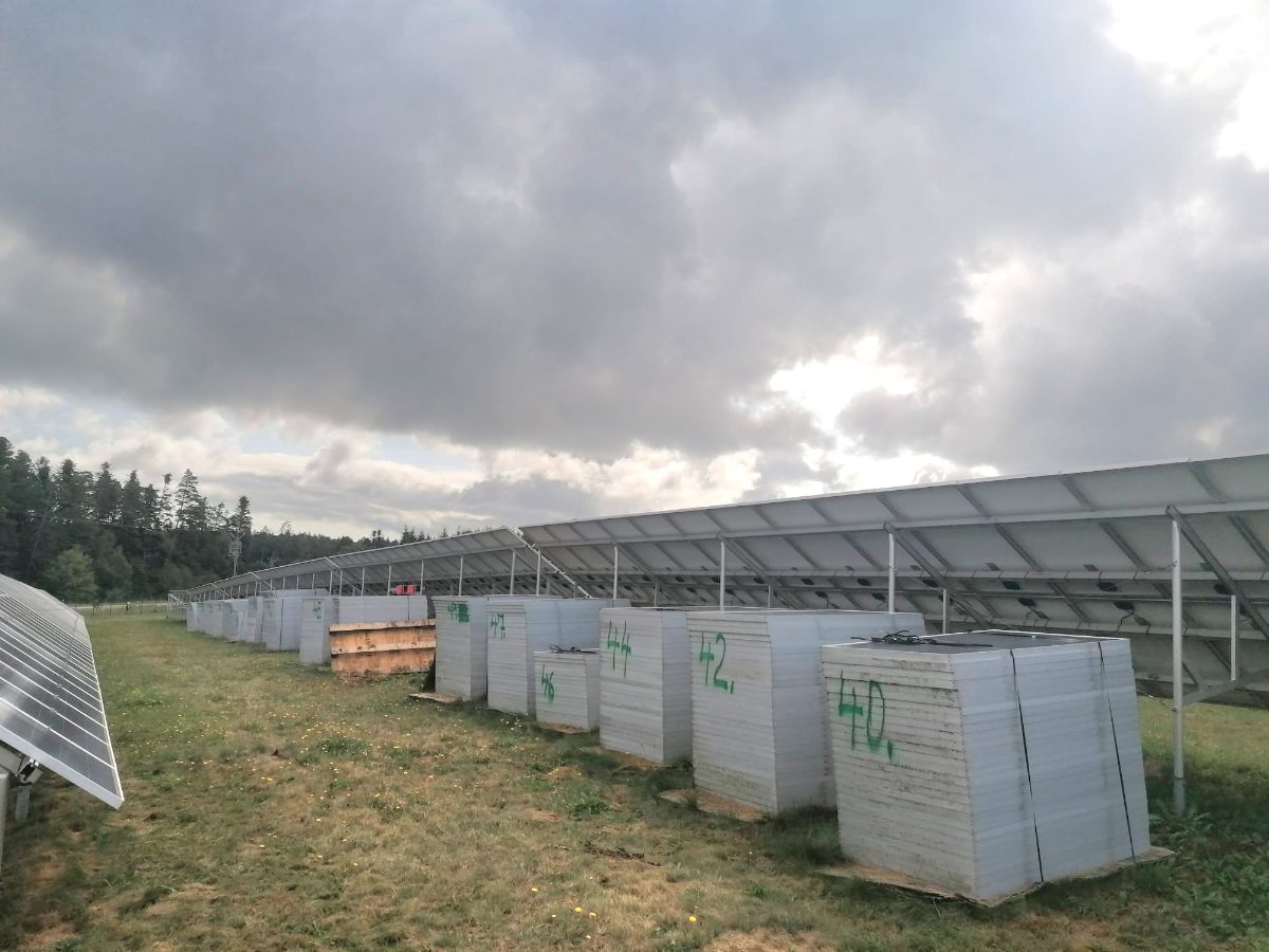 Crystalline-silicon modules taken out of service, stacked and numbered in the field beside a tracker array awaiting renovation.